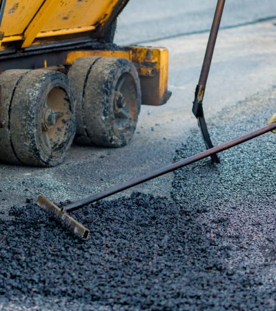 Worker regulate tracked paver laying asphalt heated to temperatures above 160 ° pavement on a runway